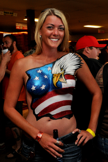 blonde woman with an american flag body painting on her chest that features a bald eagle head